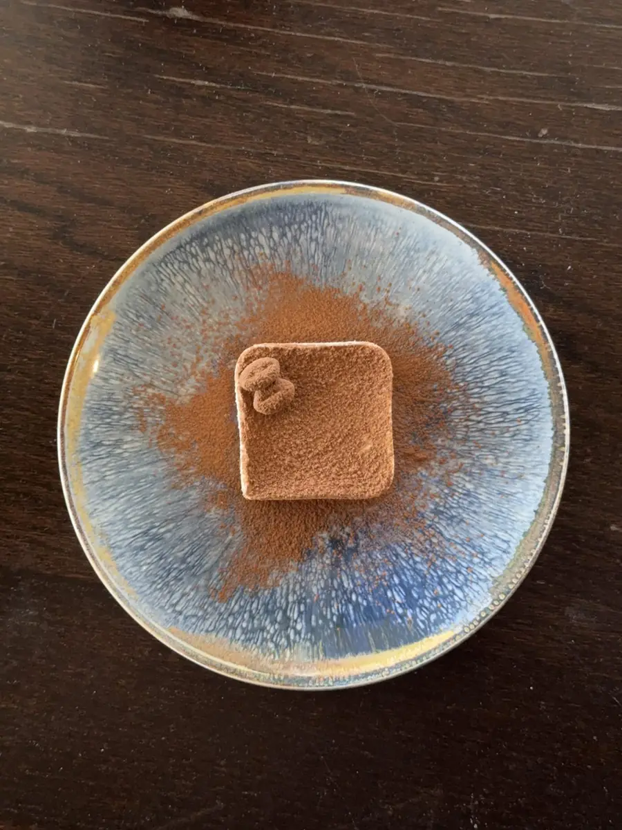 Tiramisu torte dusted with cocoa on a blue glazed plate